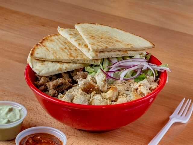 Red bowl of chicken and beef gyro with pita slices, tzatziki sauce, and a side of hot sauce.